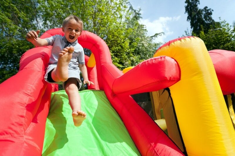 Kind auf Hüpfburg Rutsche bei einem Riesen Spielefest